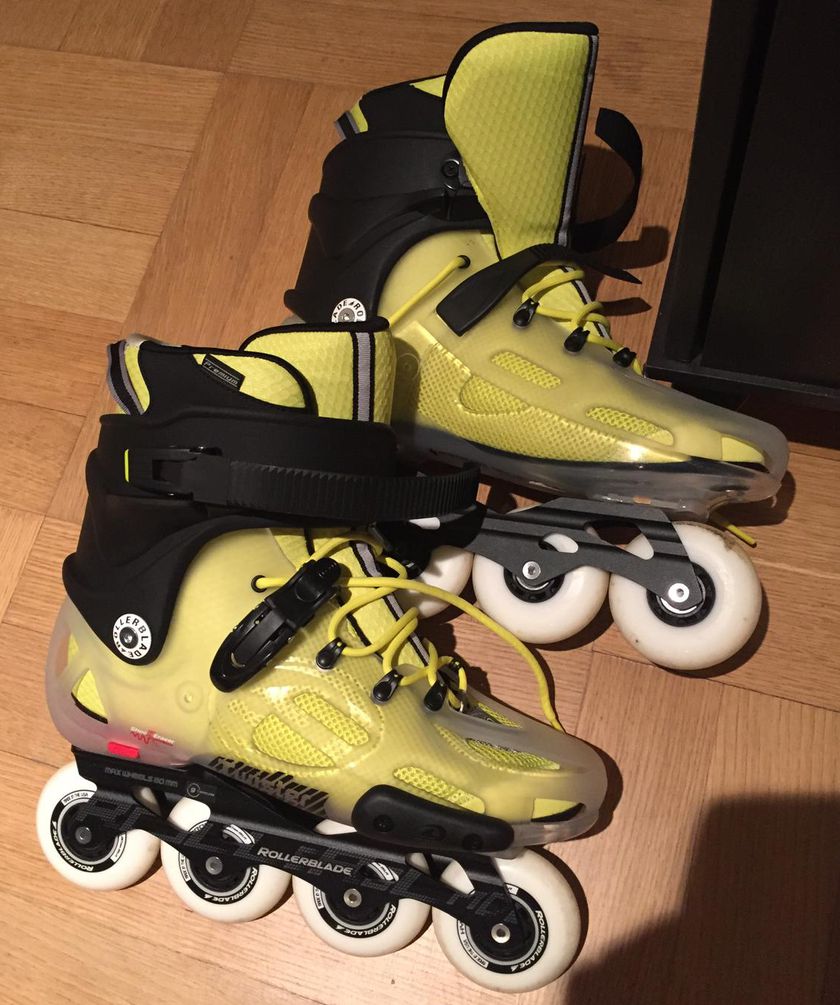 A pair of lime-yellow Rollerblade inline skates on a wooden floor